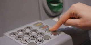 使用自动提款机的女人。女性的手在输入ATM键盘上的密码。