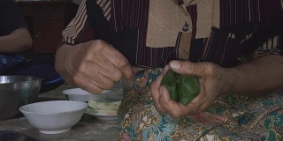 一个女人用糯米在芭蕉叶里蒸，用手做香蕉