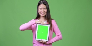 年轻美丽的亚洲女人展示数字平板电脑