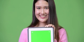 年轻美丽的亚洲女人展示数字平板电脑