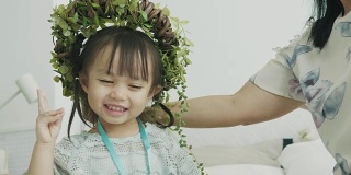 泰国可爱的小女孩戴着花叶冠微笑着，情绪愉快