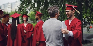 大学教授在毕业典礼后祝贺他的学生，拥抱他和握手，老师为年轻人感到骄傲，并祝他好运。
