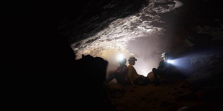 戴着头盔、提着灯笼的孩子们在山洞里探险