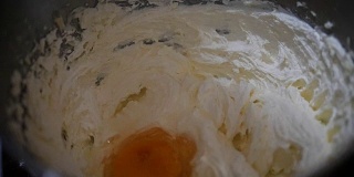 在一个金属碗里混合制作饼干的原料。手工面包师在厨房准备鸡蛋，黄油，糖和面粉。