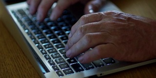 面向退休年龄人群的互联网技术。特写老人的手在笔记本电脑键盘上打字