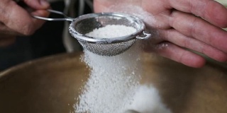女人们用手在碗里筛面粉。