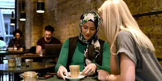 两个女人在咖啡馆里喝着热饮和吃着东西聊天