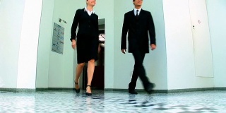 商务夫妇走出办公室中庭的电梯