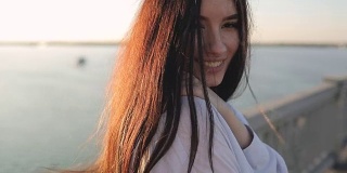 年轻微笑的女子肖像在阳光下的一座桥上，慢镜头